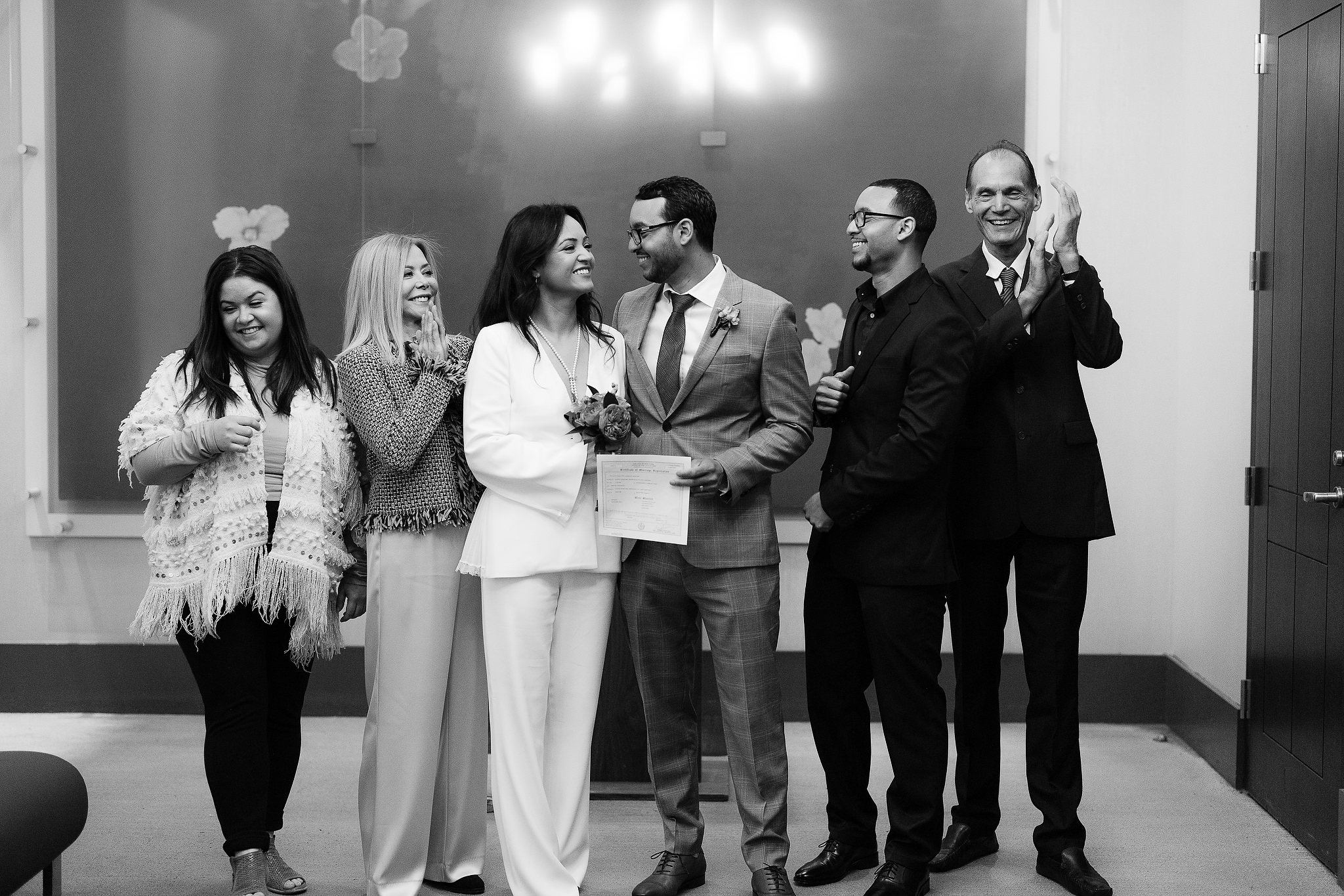 friends and family celebrate with a newly married husband and wife at city Hall in NYC