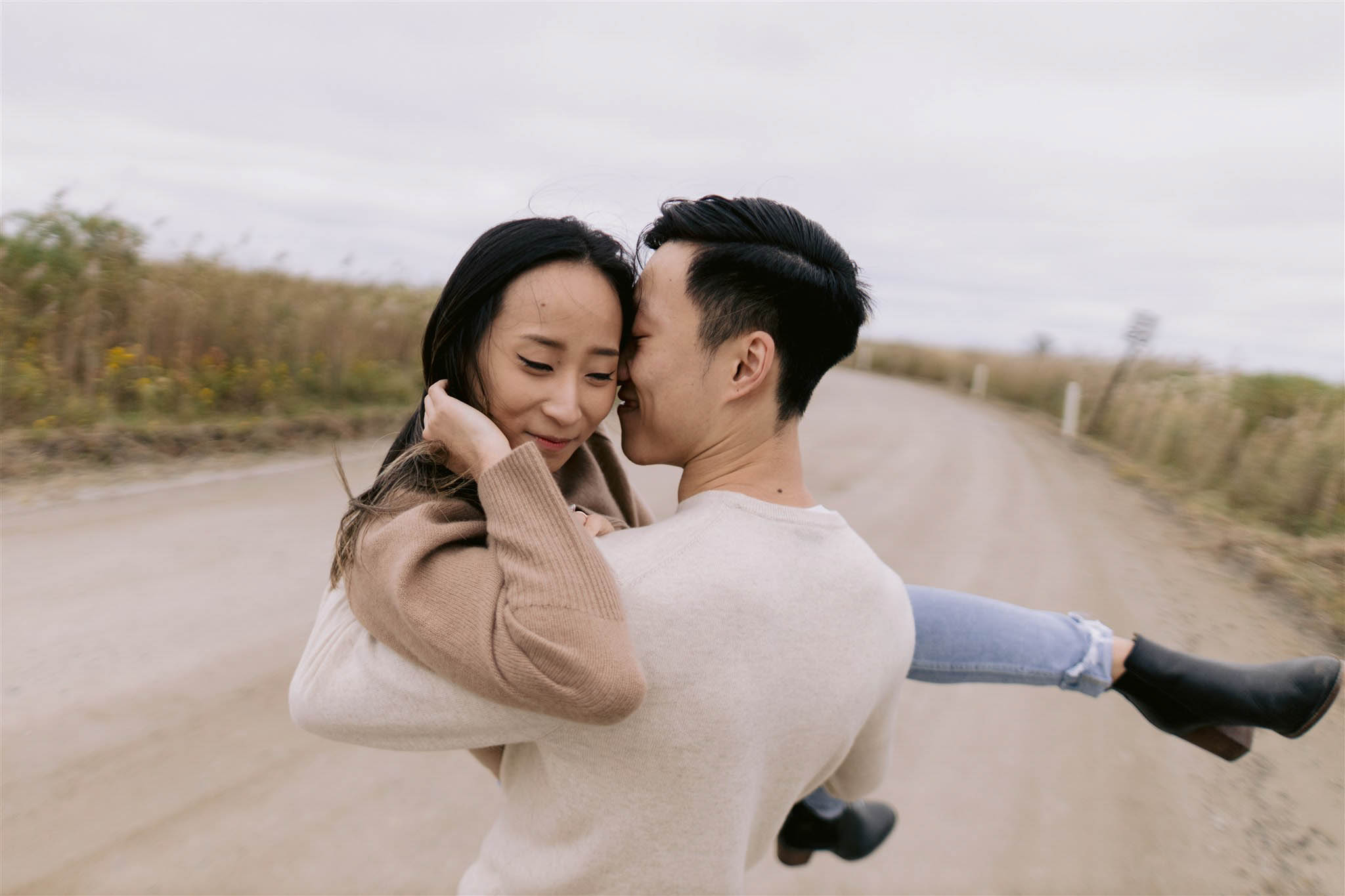 Man carries his fiancee along the road and nestles his nose into her cheek in New York's fire Island