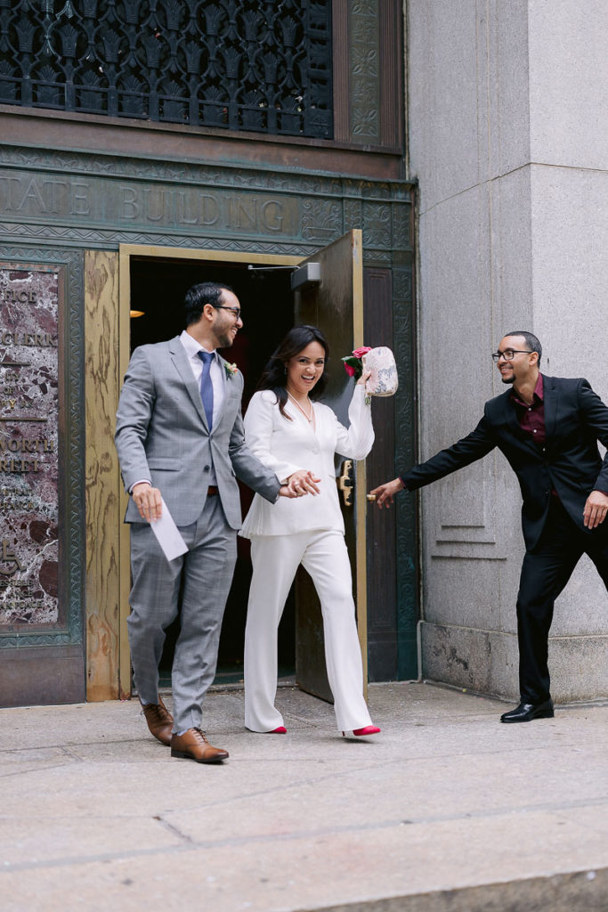 A man at New York City Hall opens the door for a newly married couple who eloped at New York's City Hall