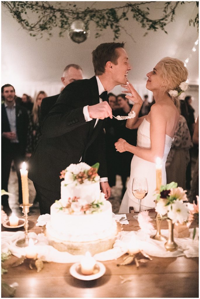 bride smears cake on her groom's face during their cake cutting. photojournalistic photography by Jenny Fu