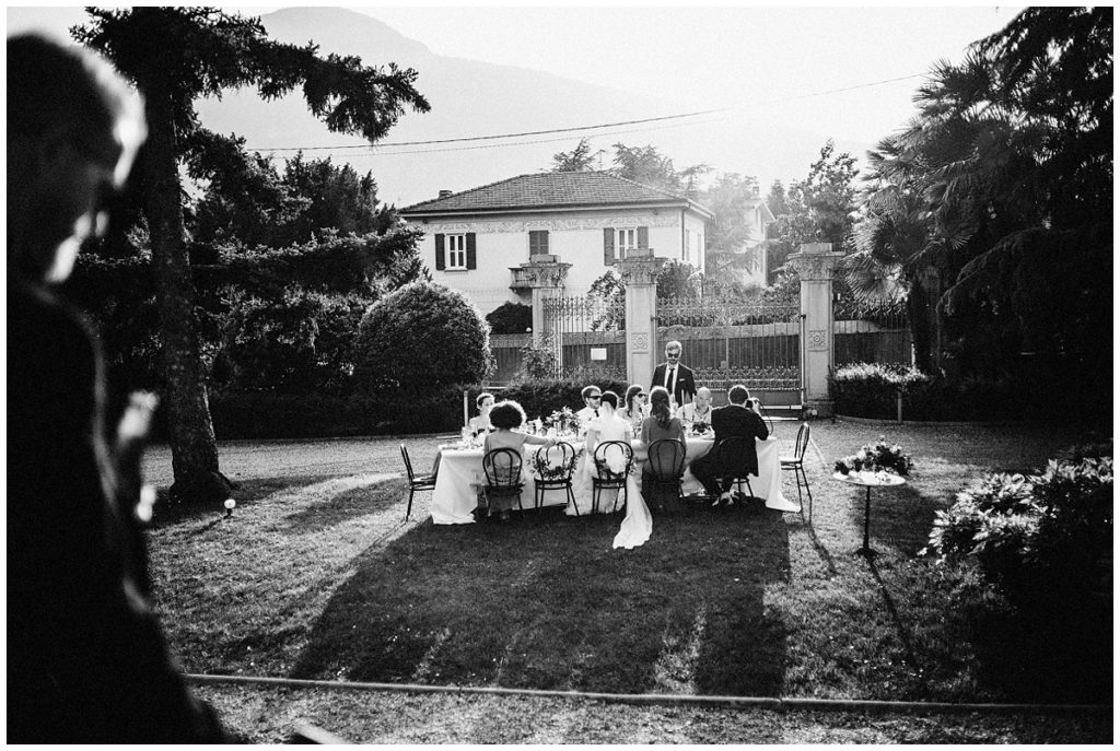 a group of wedding guests gather around a table to enjoy each other's company and toast the bride and groom in this intimate backyard wedding. Photojournalistic style by Jenny Fu studio
