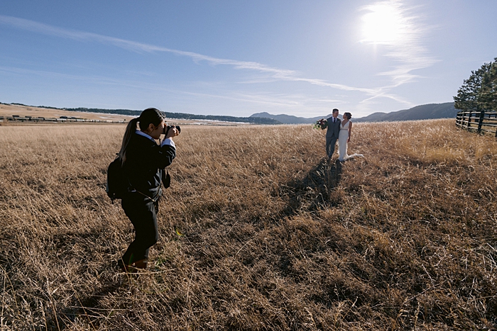 wedding photographer photographing a bride and groom in a field
