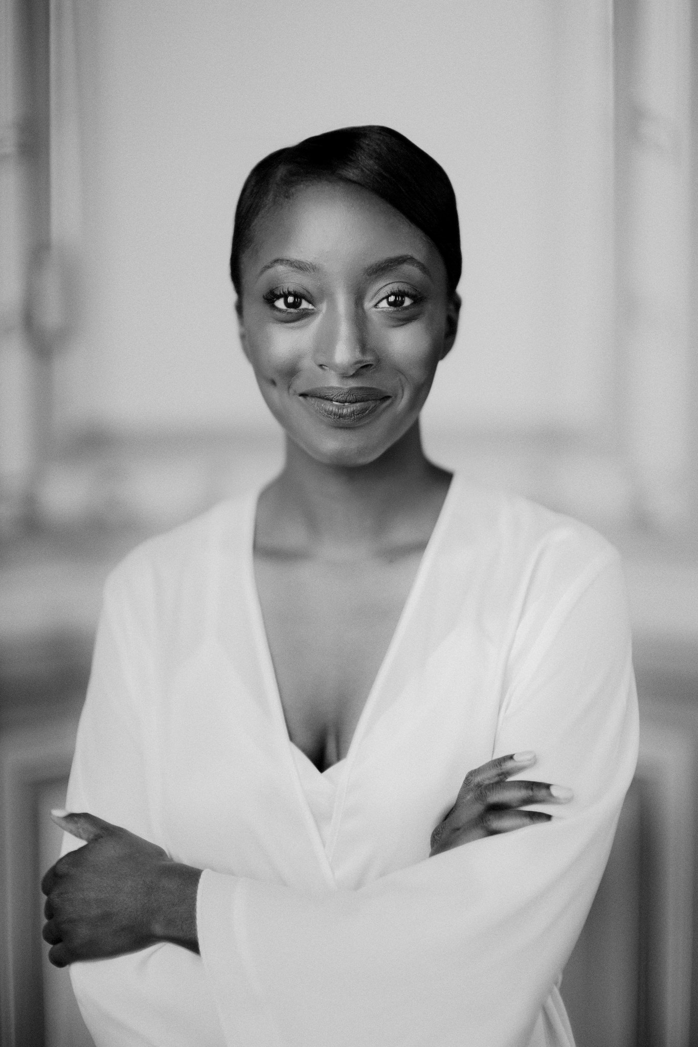 Bride with her arms crossed wearing a white robe smiling into camera