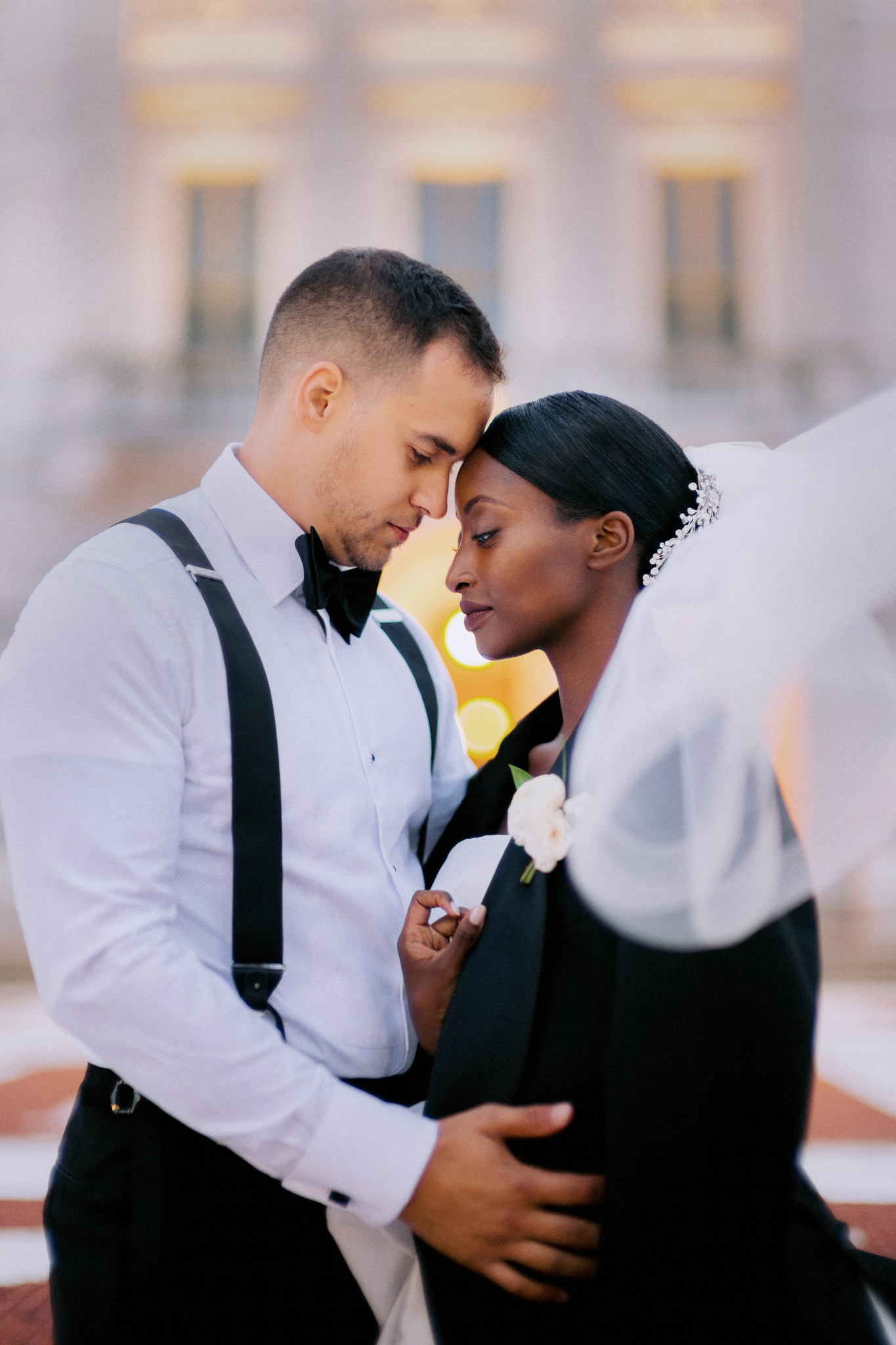 Bride and groom with their foreheads touching intimately as she wears his suit jacket over her wedding dress