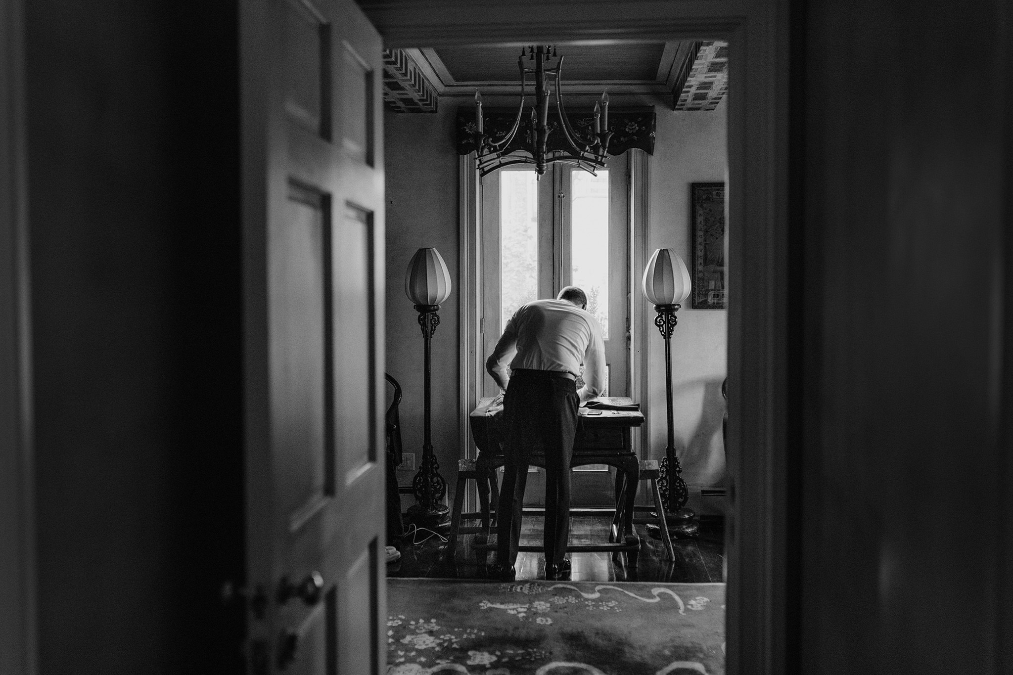 View through doorway of groom bending over table in antique style room