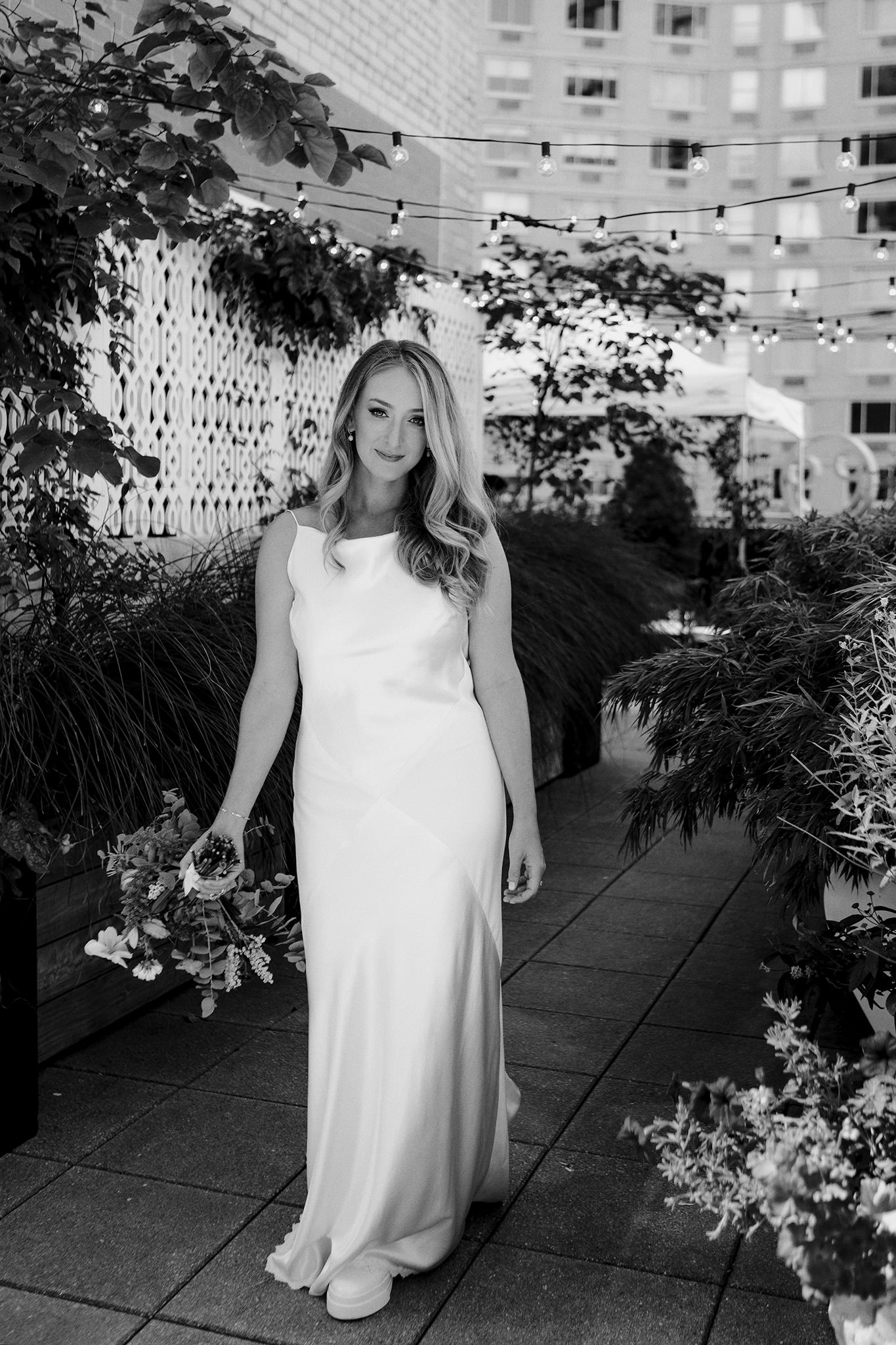 Smiling bride standing on her families rooftop patio in Manhattan on her wedding day
