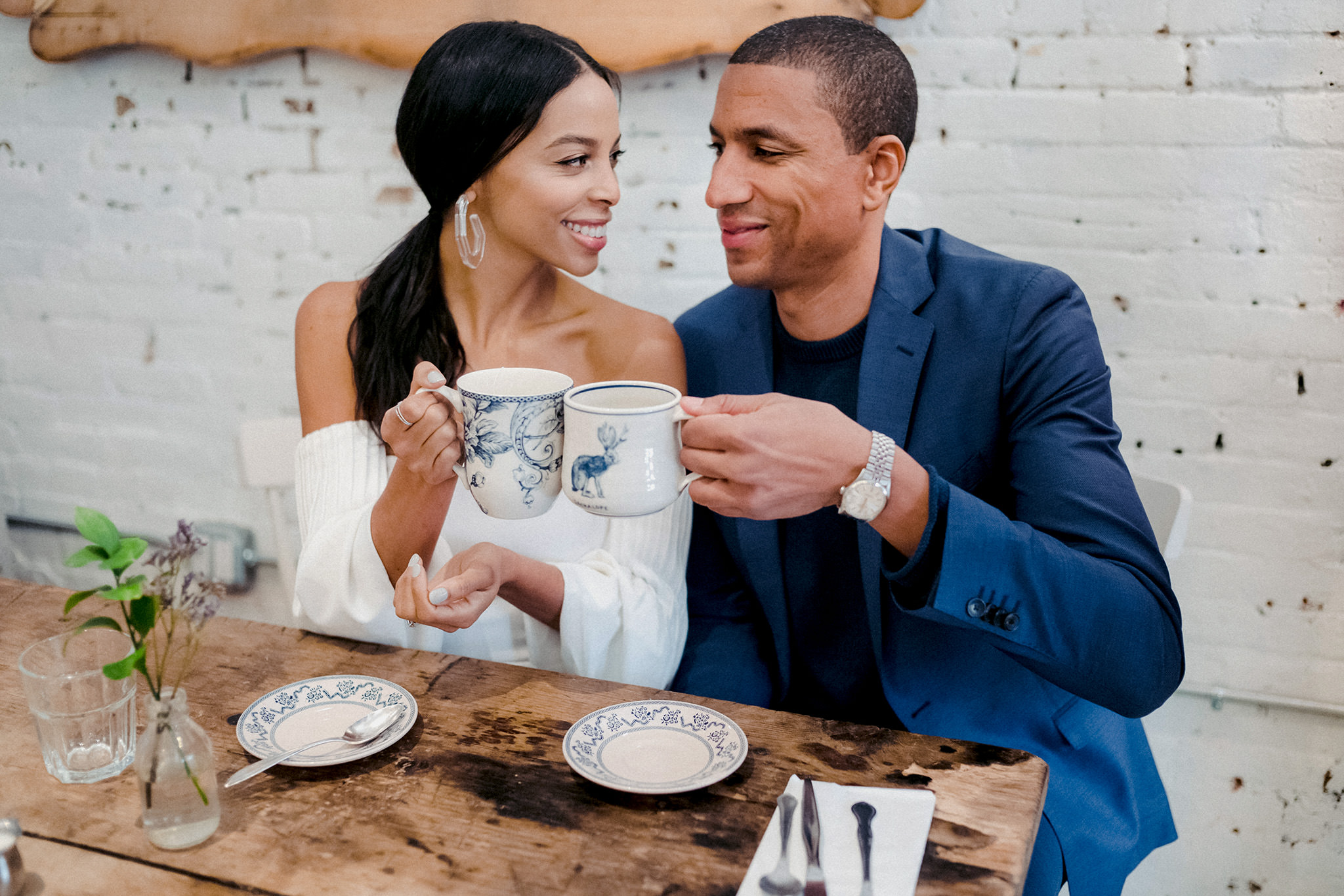 Man and woman clinking their coffee cups at a coffee shop.