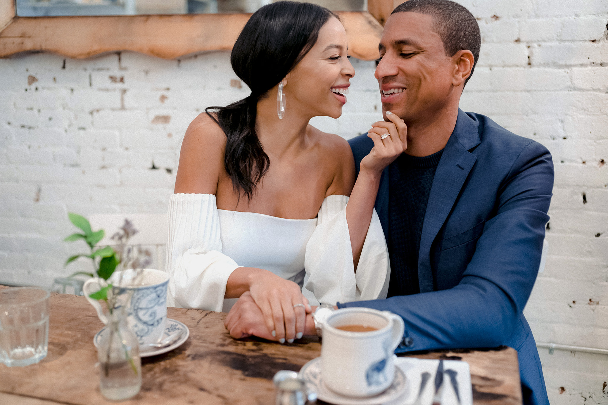 Woman holding her fiances hand at a coffee shop during their indoor engagement session