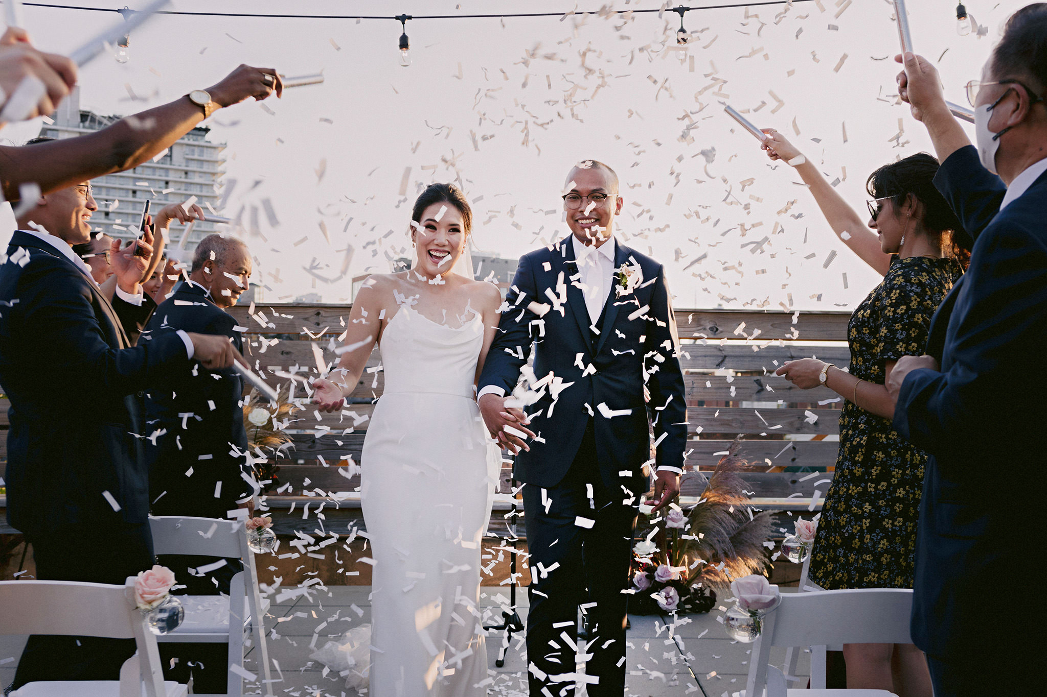 Bride and groom walking down the aisle surrounded by their friends and family
