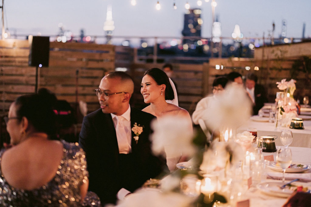 Bride smiling at her wedding guests over a candle lit dinner