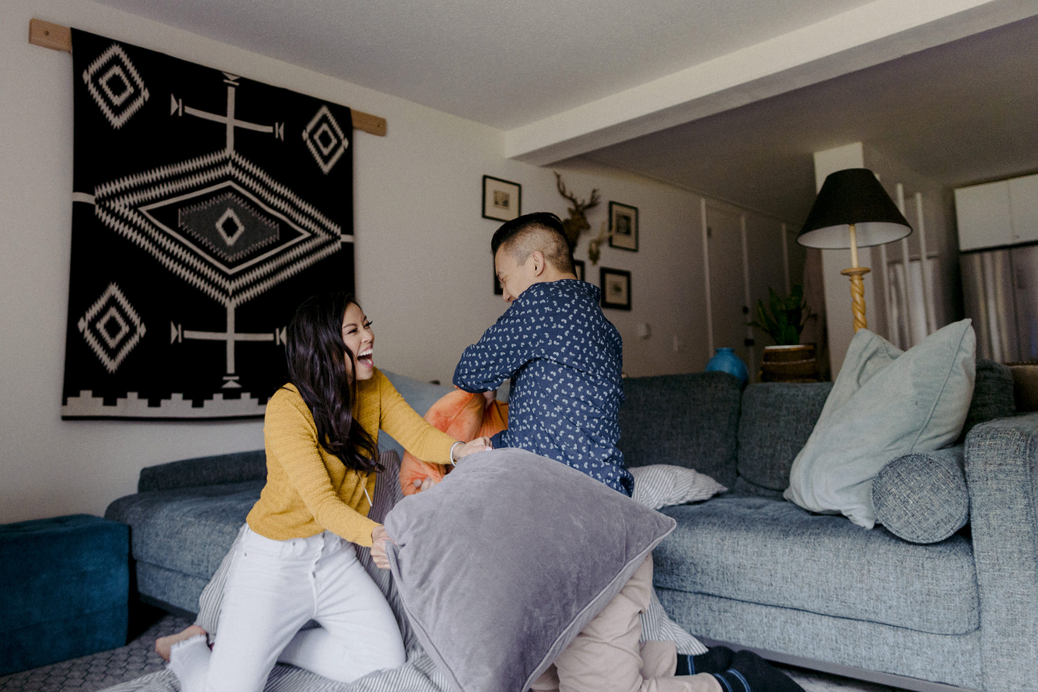 Engaged couple having a pillow fight in their living room