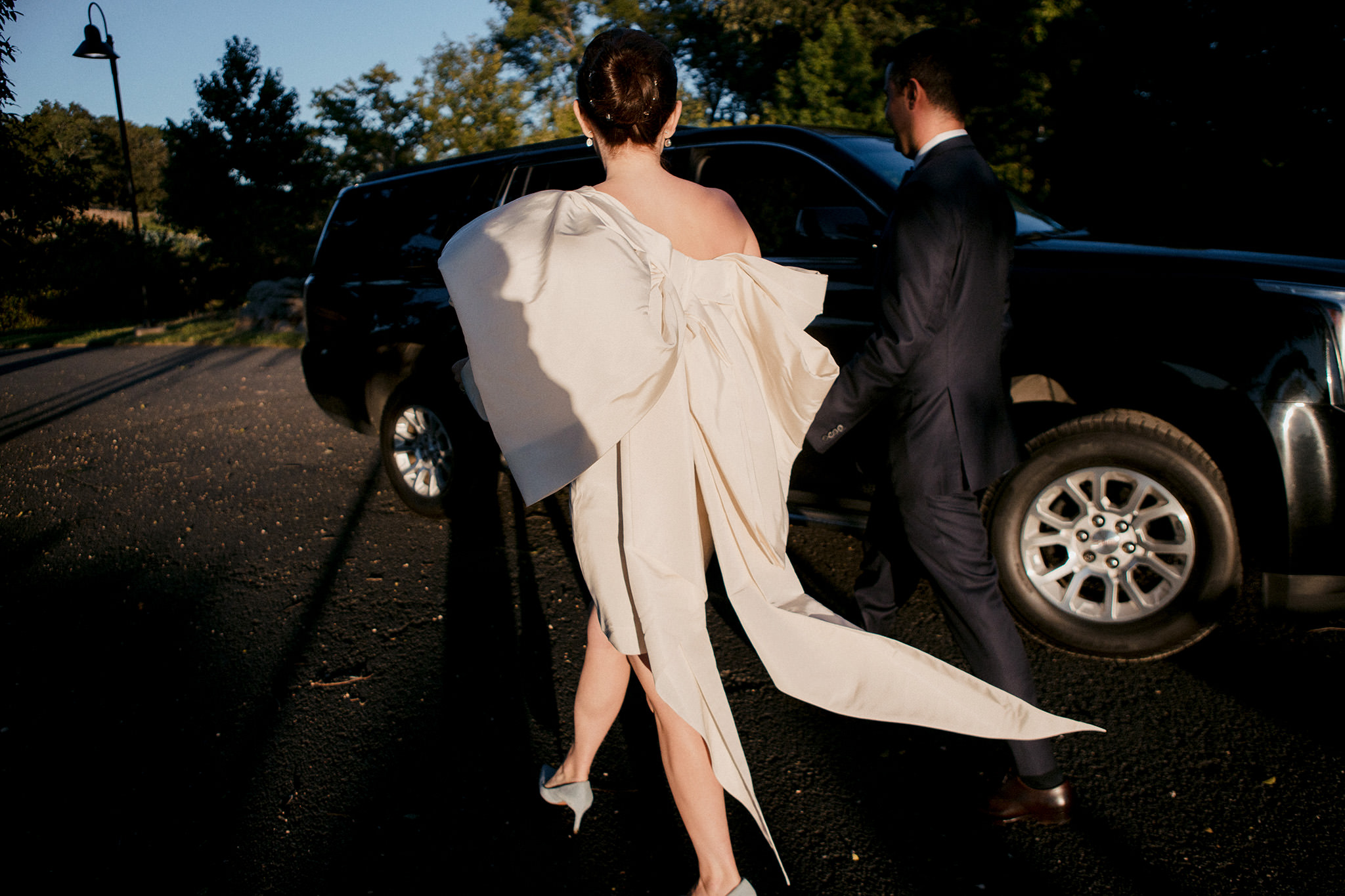 Bride walking into an SUV wearing Carolina Herrera gown
