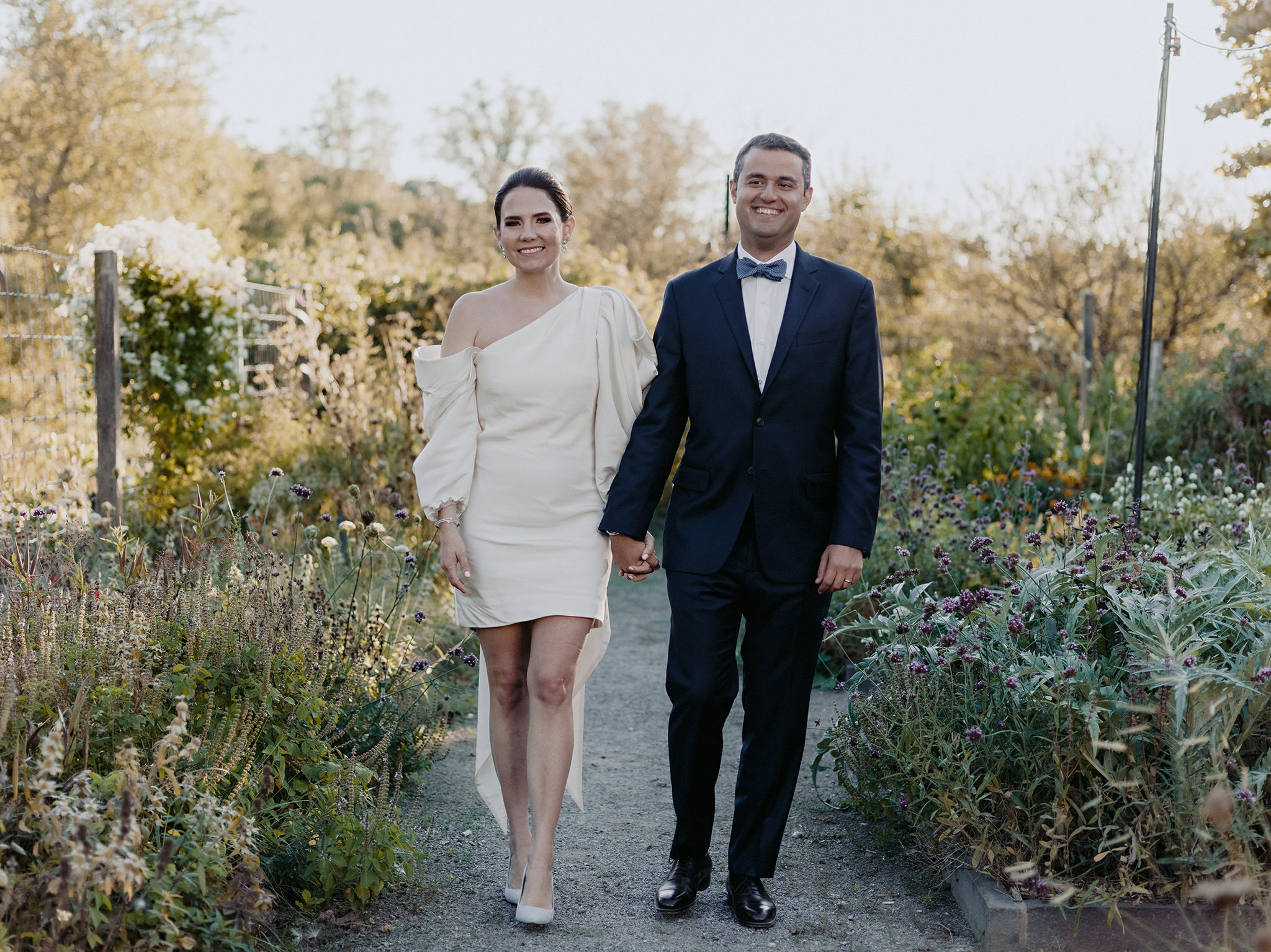 Bride and groom hold hands in garden at Blue Hill at Stone Barns
