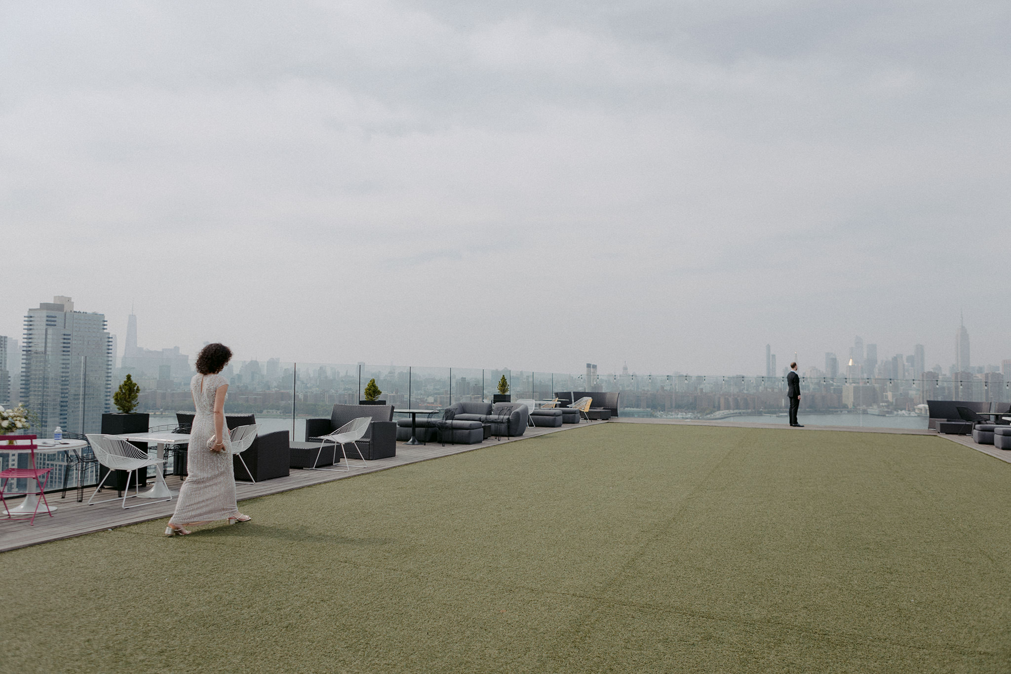 Bride walks towards her groom on their elopement wedding venue at The William Vale. Groom is looking out at Manhattan skyline
