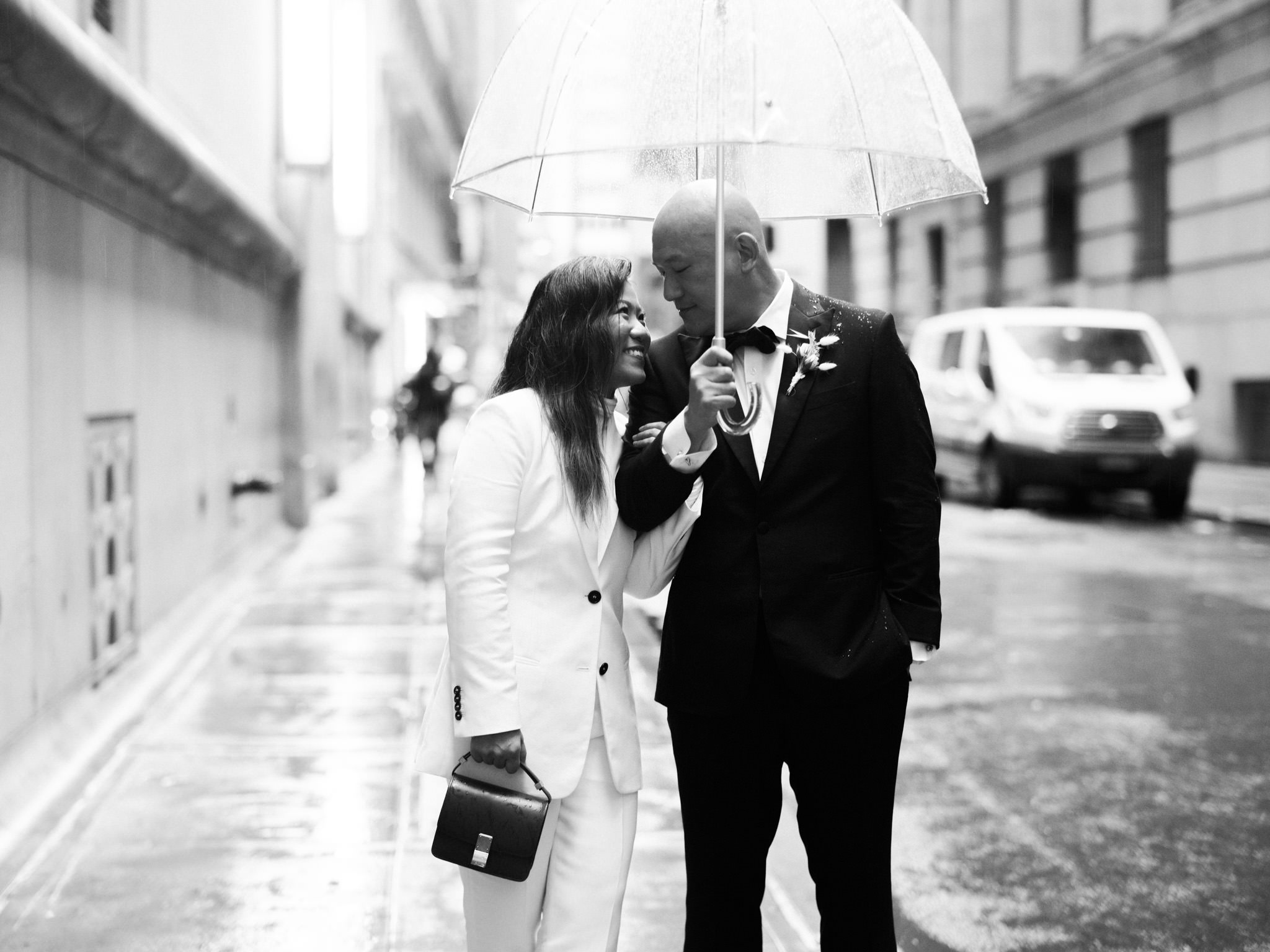 Bride and groom under an umbrella in the rainy streets of New York City