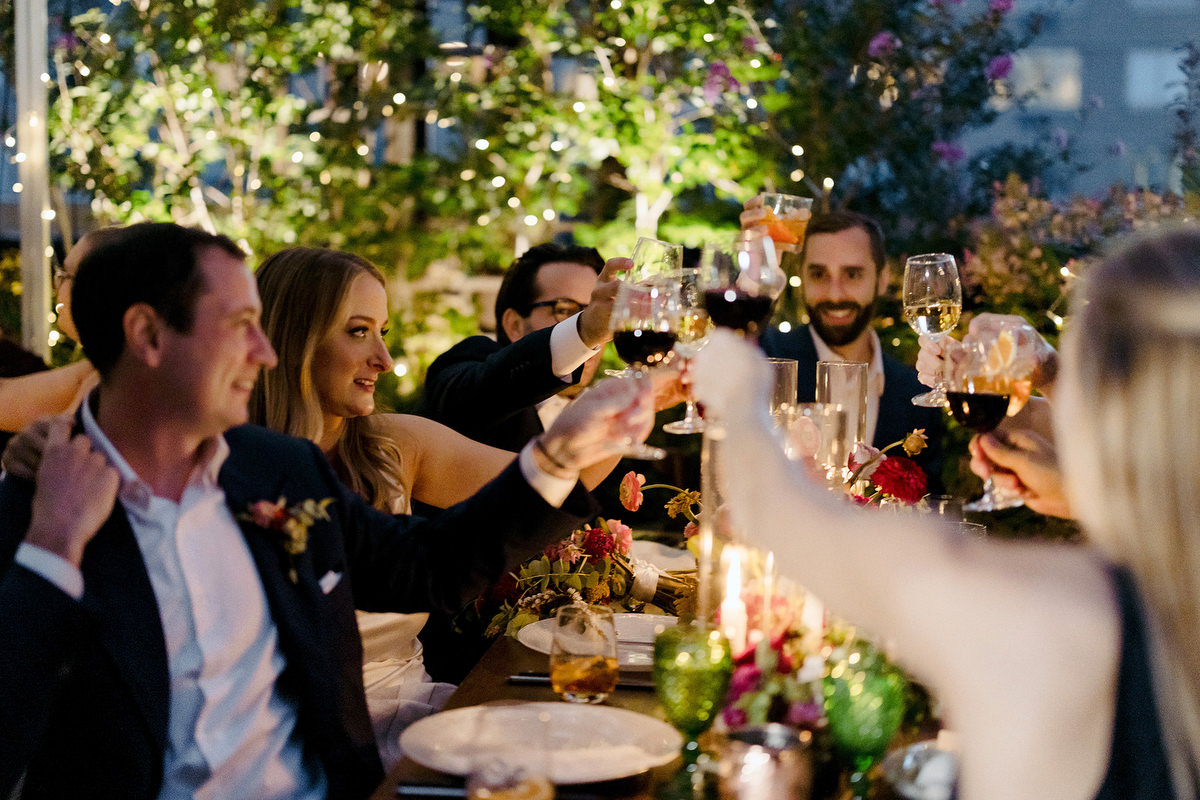 Wedding guests cheers their wine glasses over candlelight