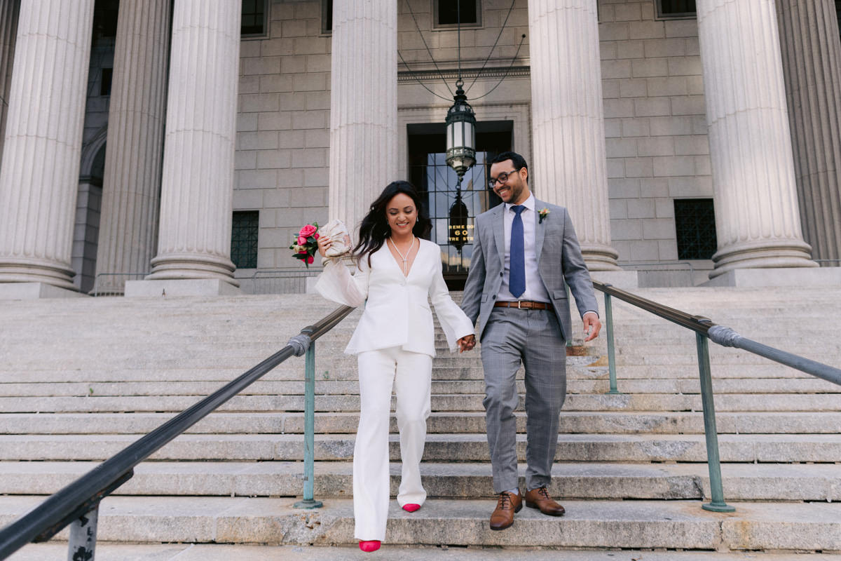 Bride and groom walk down the steps at city hall, foley square, Supreme Court building in NYC