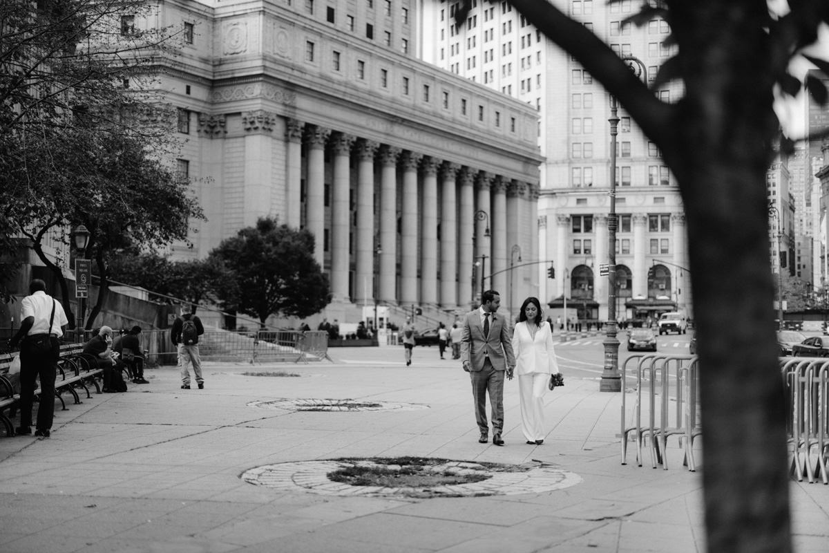Bride holding grooms hand outside city hall, foley square, Supreme Court building in NYC