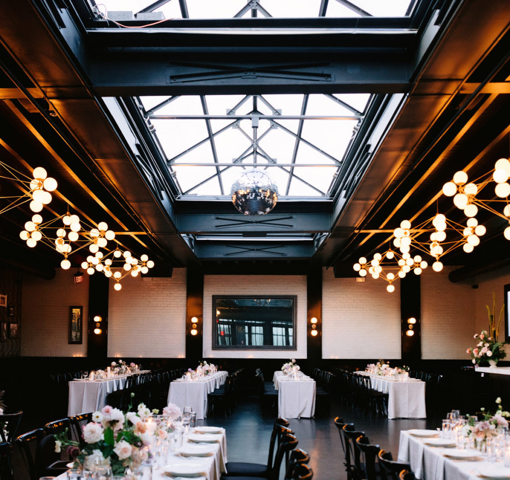A wedding with banquet tables covered in flowers, ordered by an NYC wedding planner