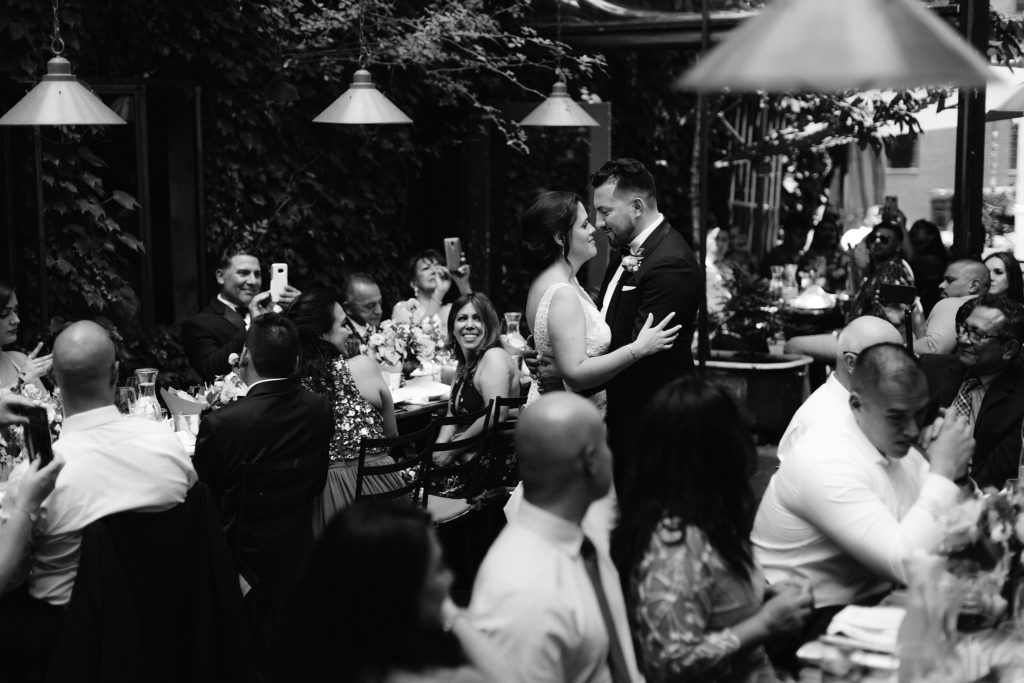 A bride and groom dance at their wedding reception while their wedding photographer takes timeless photos