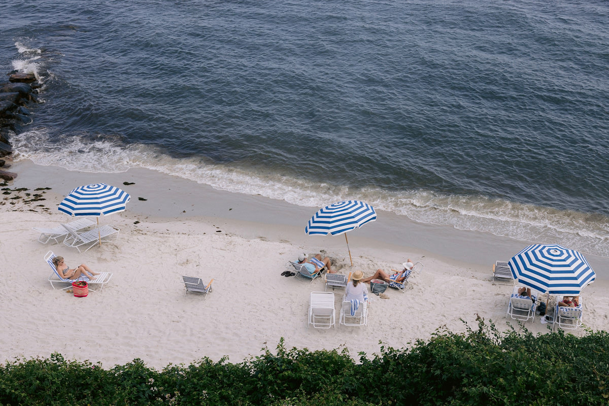 Three blue and white striped umbrellas on a beach in Cape Cod.
