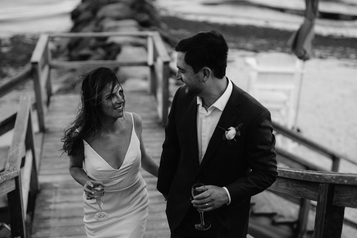 A bride and groom walk up wooden stairs from the beach in Cape Cod.