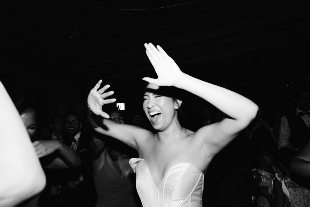 An Asian-American bride dances with her wedding party at their wedding reception
