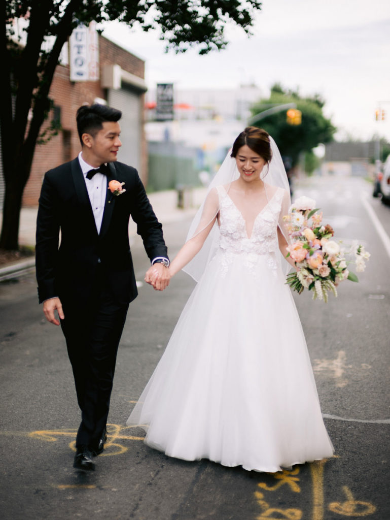 A bride in a princess wedding dress holds hands with her groom