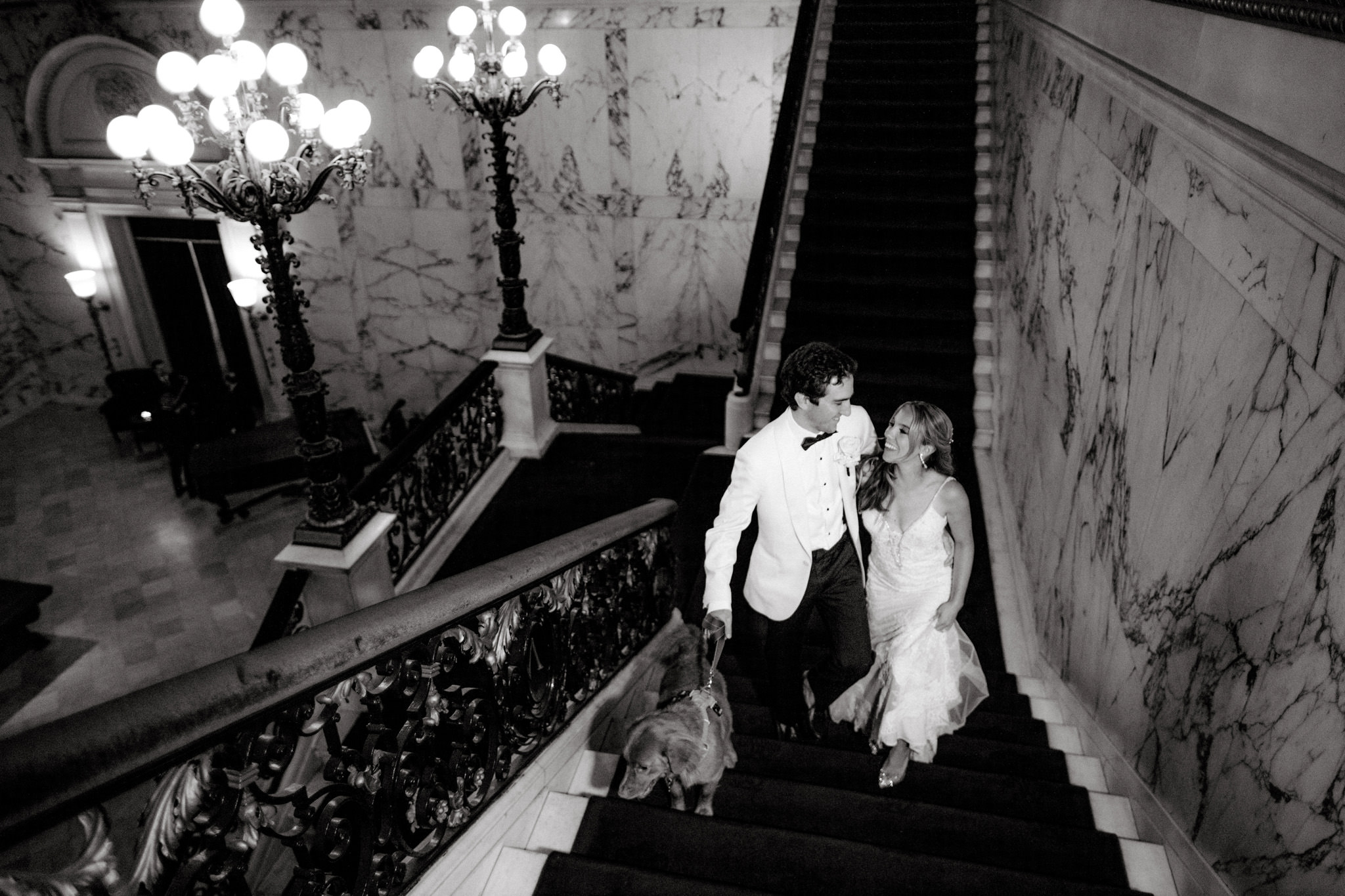 A couple smiles at each other on a staircase on their wedding day
