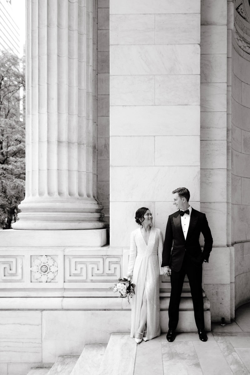 Bride and groom leaning against the huge columns in NYPL